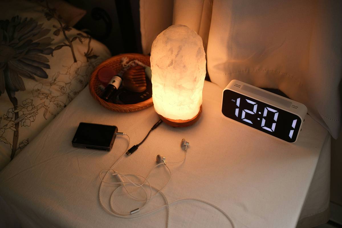 A calming sound machine placed beside a bed emitting soothing ocean waves.