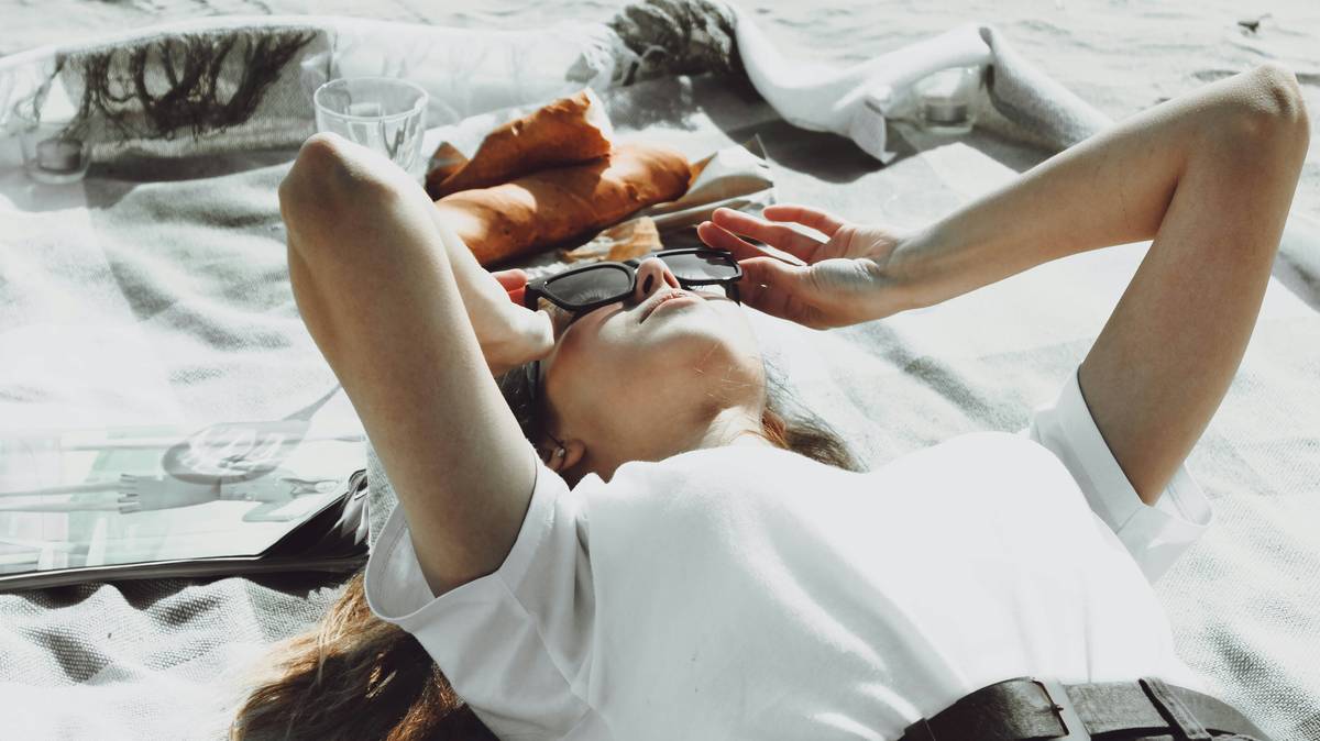 Attractive girl in glasses is lying on plaid. Portrait of the beautiful girl close-up. Young pretty woman. Young woman outdoors portrait.
