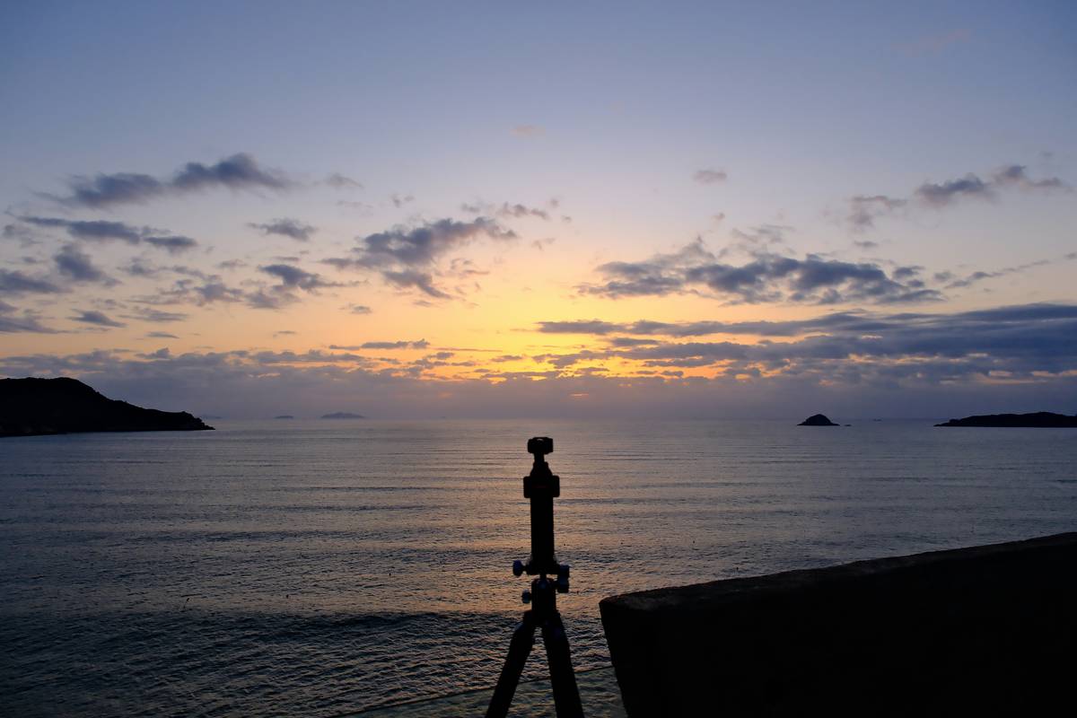 Sunset over the ocean with a tripod in foreground