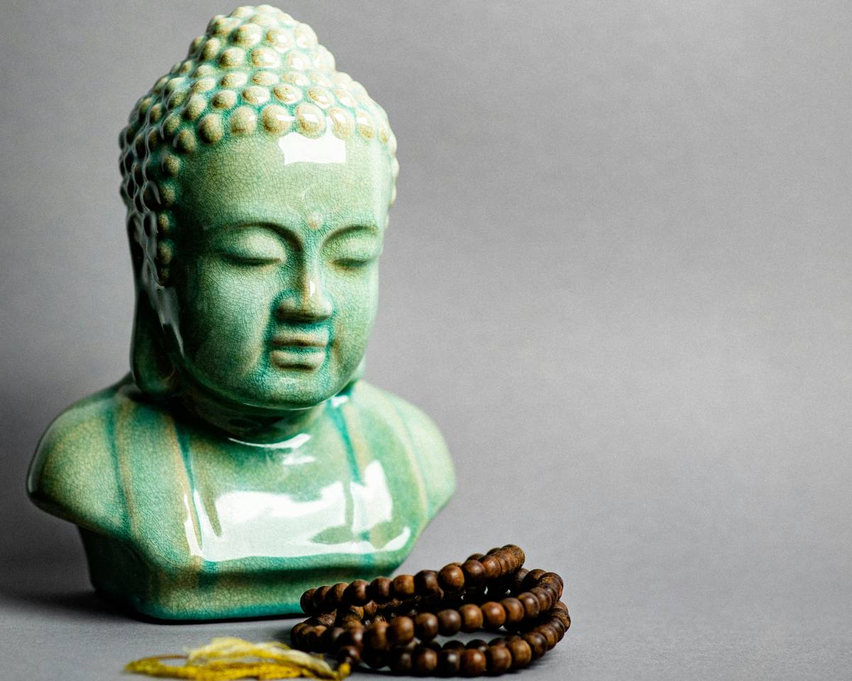 A buddha statue next to a beaded bracelet